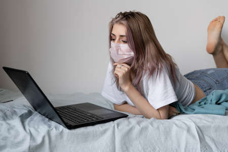 Young business woman working from home with a laptop, wearing a protective mask. Remote ability to visit the workplace. A face shield is worn.の写真素材