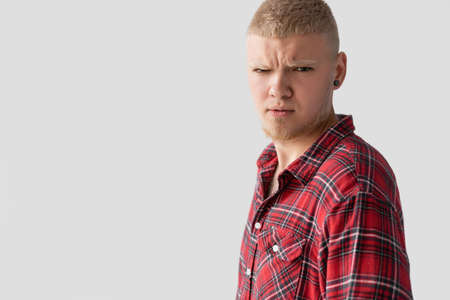 young handsome blond man dressed in a red shirt with a serious look looks at the camera.の写真素材