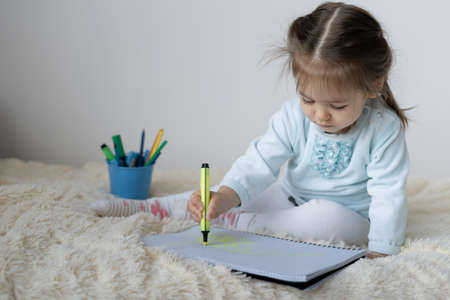 We sit at home, a little girl alone on the bed.の写真素材