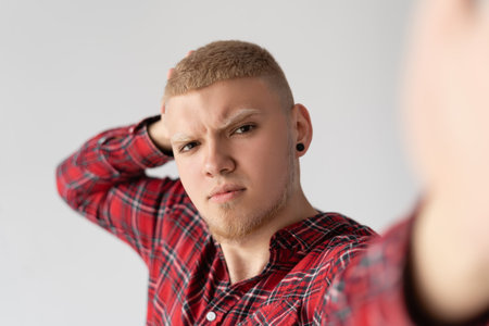 young man man makes selfie on the phone. guy with blond hair, blond. He photographs himself.