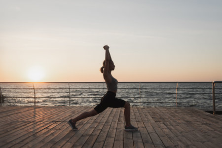early morning dawn, a female athlete does a workout. Physical exercises for the body. Yoga classes. Sunrise. Copy spaceの写真素材
