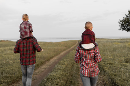 rear view happy family walks in nature. Mom, dad, two kids sons. Walk in the fresh air. Parents...