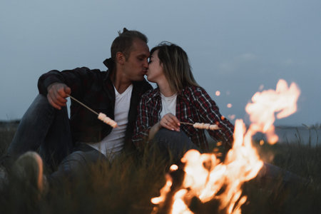 man kisses a woman in the evening in the fresh air. Family outdoor recreation. bonfire burns place...