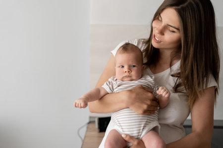 young beautiful mother holds a small infant in her arms.