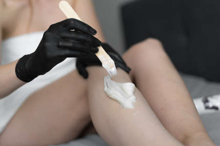 Unrecognizable woman working with sugar paste in a bedroom on a bed at home. Homemade paste, beauty procedures, cosmetologyの写真素材