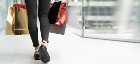 Close-up of female legs walking in the mall. Colored shopping bags. Baner place for text. Copy spaceの写真素材