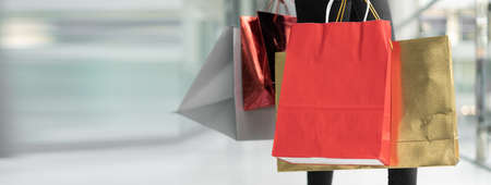Female hands are holding several colored packages. Shopping mall concept. Baner. Copy space.の写真素材