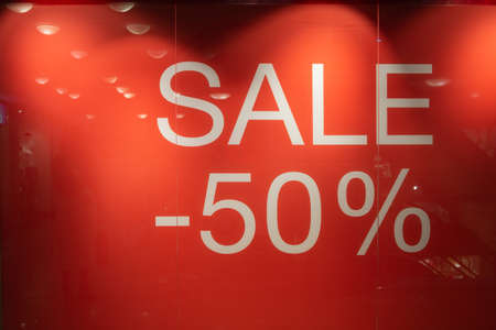 Large red sales poster at the entrance to a retail sale of clothing. Discount labels at the entrance to the store. Sale up to 50 percent. Seasonal Sale, Black Friday and Shopping Conceptの写真素材
