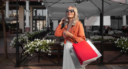 Close up portrait of woman shopaholic. She stands in the street holding shopping bags.の写真素材