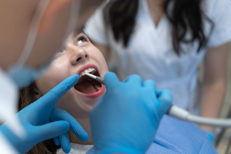 male dentist examining a patient with instruments in a dental clinic. The doctor conducts dental...