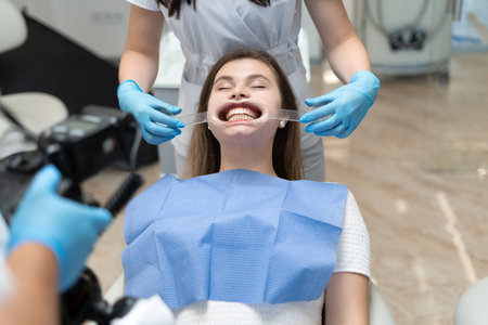 girl with dental caps sitting in the doctors office for teeth whitening procedure. procedure in...