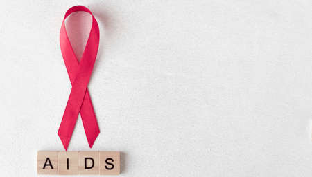 Concept for World AIDS Day. Red ribbon near wooden letters. Baner. Copy space.の写真素材