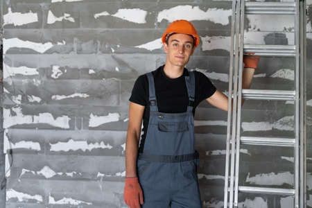 worker with orange helmet helmet near a wall of stones. Worth smiling. Copy space.の写真素材