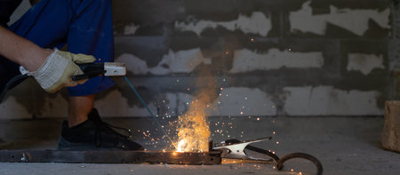 Welder works welding metal and sparks, close-up hands. Copy space.