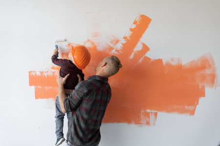 repairs his house, the father keeps his son and he helps him paint the wall with a roller, copy...