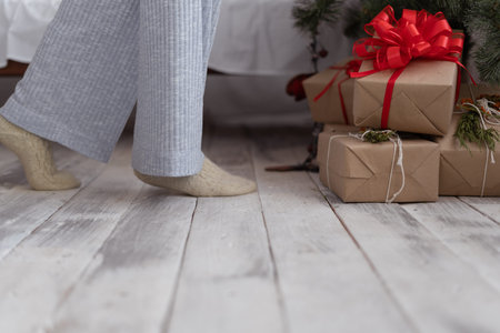 Beautiful female legs in pajamas fit the Christmas tree. Christmas gifts boxes copy space