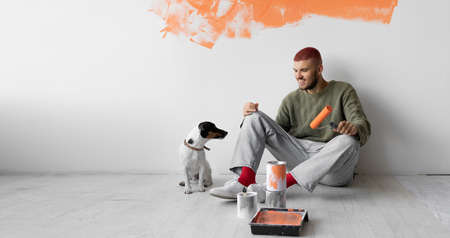 young man sits on the floor, dog jack russell beside him. Home renovation concept. Copy spaceの写真素材