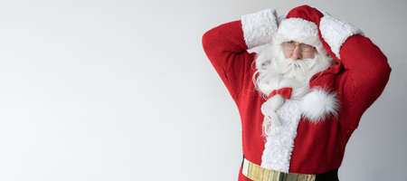santa claus is standing on white, holding his head with his hands. Copy spaceの写真素材