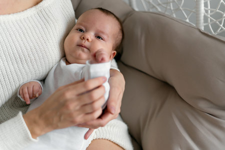 Mom and baby are sitting on a wicker chair. A woman holds her daughter's hand. Motherhood and childhood concept.の写真素材