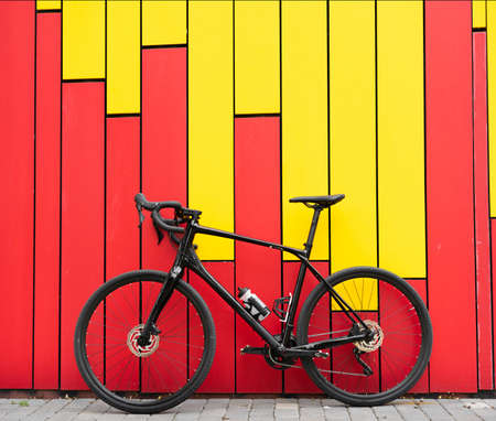 A black metal bicycle stands on the street near a bright wall. Bicycle garage. Sports in people's lives. Place for your text.の写真素材