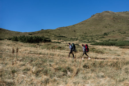couple in love tourists man and woman stand walking along a mountain path, large backpacks. Hiking...