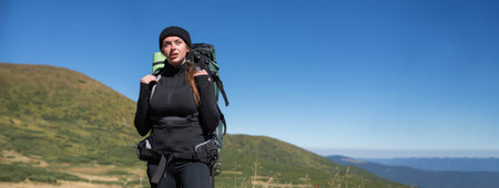 Young woman tourist hiker with a large backpack stands on the top of the mountain. Baner.の写真素材