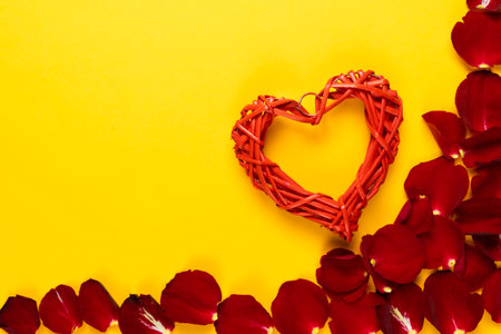 flat lay, red heart lies on an orange background near rose petals. Concept to celebrate valentines day. Copy space.の写真素材
