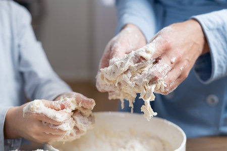 Mother and daughter with flour together in the kitchen prepare dough in a bowl.の写真素材