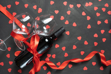 A bottle of wine and two large glasses on a black concrete background. valentines day concept.の写真素材