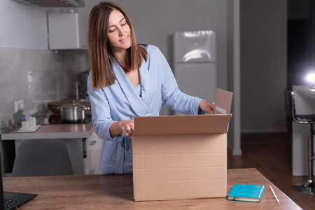 young caucasian woman unpacks a box at home on a desk. online shopping concept, fast delivery.