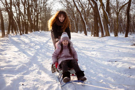 Child girl in a colorful clothing running in a snowy winter park . Little winter girl in fairy ice forest. Walk in winter forest. Expressing positivity, true brightful emotions, smiling. 4kの写真素材