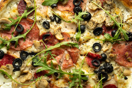 Top view of pizza with olives, salami, arugula and cheese in a box. Delivery of orders from a pizzeria.の写真素材