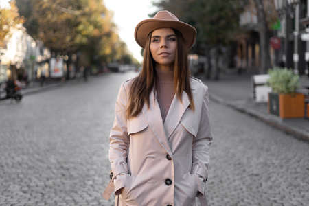 Close-up fashionable woman portrait of a young trendy girl posing in a city in Europe, autumn street fashion, wearing a retro hat popular before 60s.の写真素材