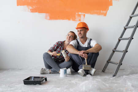 home renovation concept, man and woman sit on the floor near the wall with orange stain.の写真素材