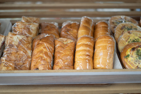 Wooden shelves with fresh bread and baguettes in the supermarket. Products in the bakery section of...