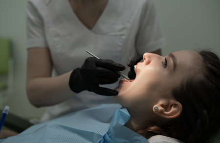 Close-up examination of the patients oral cavity by the dentist in black medical gloves with tools....