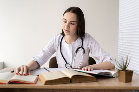 Portrait of Caucasian female doctor reading medical books in search of information about rare diseases science, medicine and pharmacy concept.の写真素材