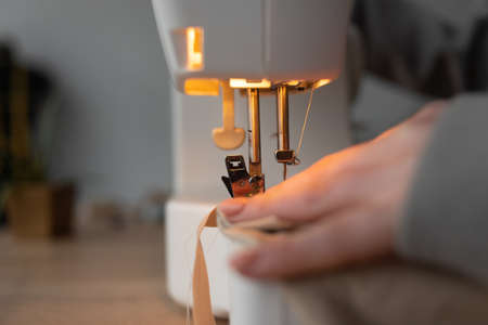 Sewing process, close-up of female hands near the needle of a sewing machine.の写真素材