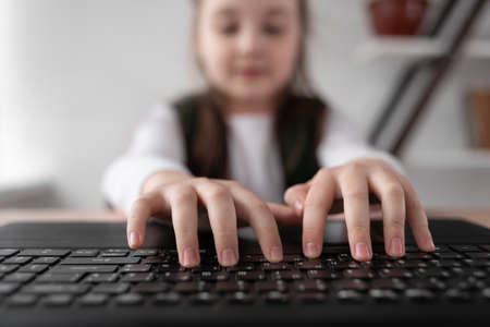 Close-up of kids hands are typing text on the keyboard. Webcam view.の写真素材