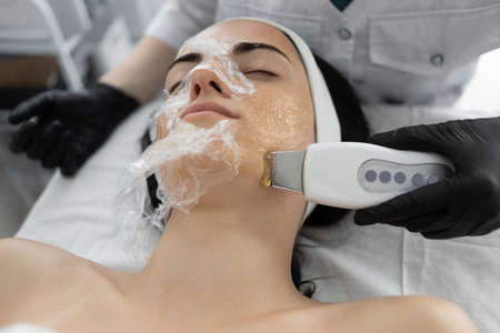 Beautiful young woman at the reception at the beautician, ultrasonic face cleaning close-up side view. Cosmetic procedure in a modern beauty salon.の写真素材
