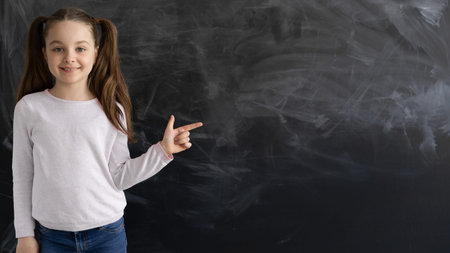 a Caucasian girl, a schoolgirl, is standing against the background of an empty chalk board. the...