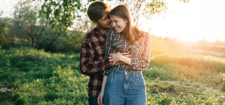 Two young laughing people are hugging in the park in nature. Happy family in casual clothes....