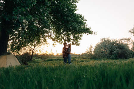 Love story a guy with a girl kissing in the forest. Loving married couple on a romantic date in the park. Travelers in nature. Love and relationship conceptの写真素材