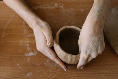 Top view of female hands sculpt utensils from clay.