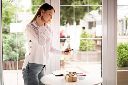 small business owner takes a photo of the product in a cafe on the table. Side view of a girl with a...