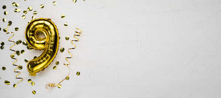 golden foil balloon number nine. Birthday or anniversary card with the inscription 9. gray concrete background.の写真素材