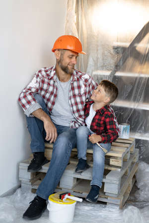 Restoration, decoration and painting of the house, father and son sit during the renovation of the house and take a break. parenting help concept.の写真素材
