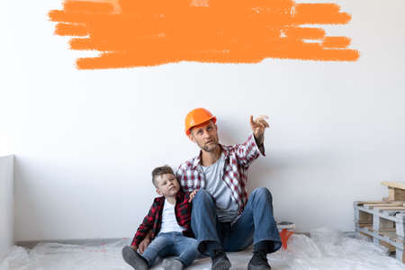 Happy young family is renovating their house, father is holding son sit on the floor. White moaning with space for text.の写真素材