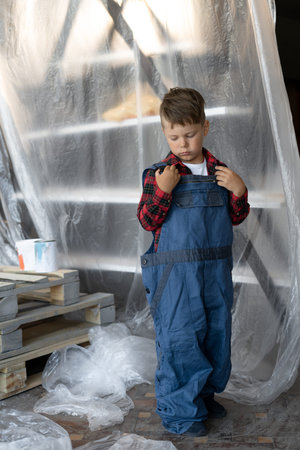 Boy builder. A child in a blue overalls at a construction site. Suit for the builder.の写真素材