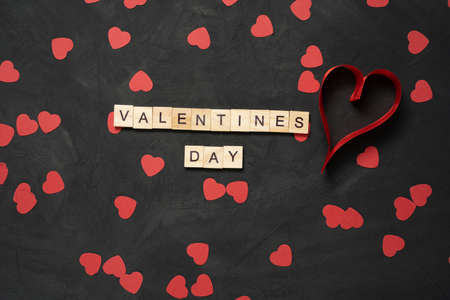 Valentines Day text word wooden blocks with paper hearts on black cement floor. Valentines Day 14 February holiday. minimal concept.の写真素材